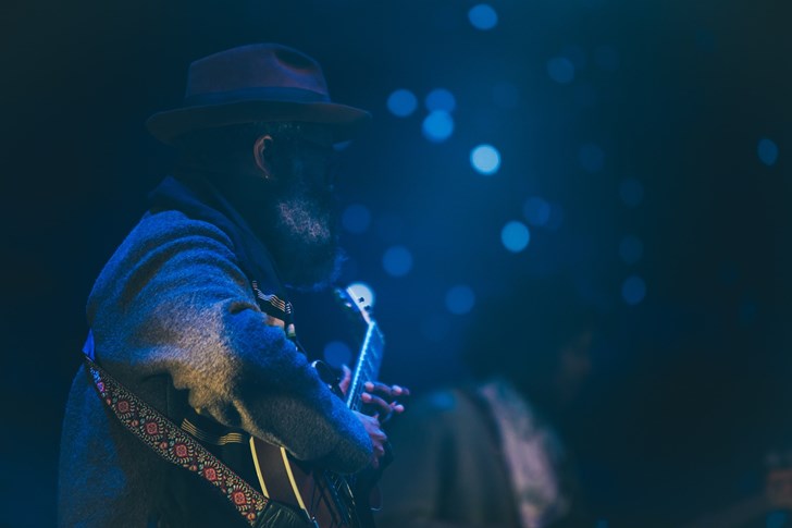 Man playing guitar to a stadium of people at a festival.